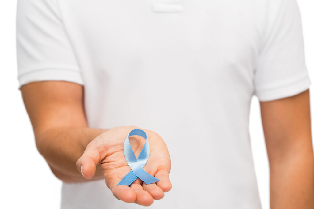 Male hand holding blue ribbon for Prostate Cancer Awareness Month