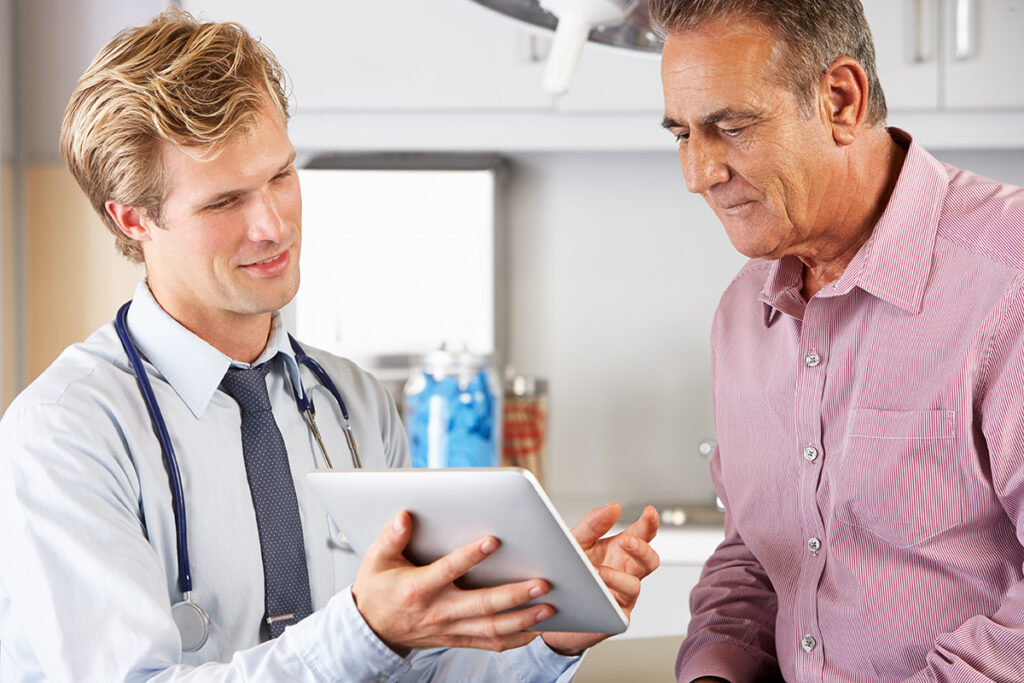 Young doctor showing male patient something on tablet screen