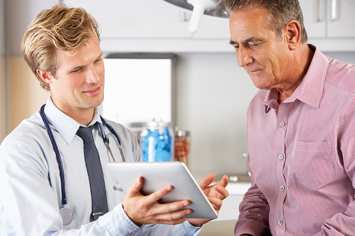 Young doctor showing male patient something on tablet screen