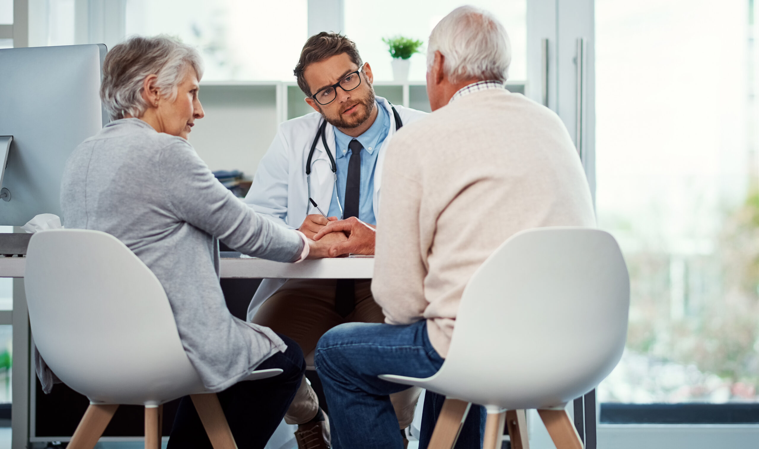 Male doctor talking with older couple at desk