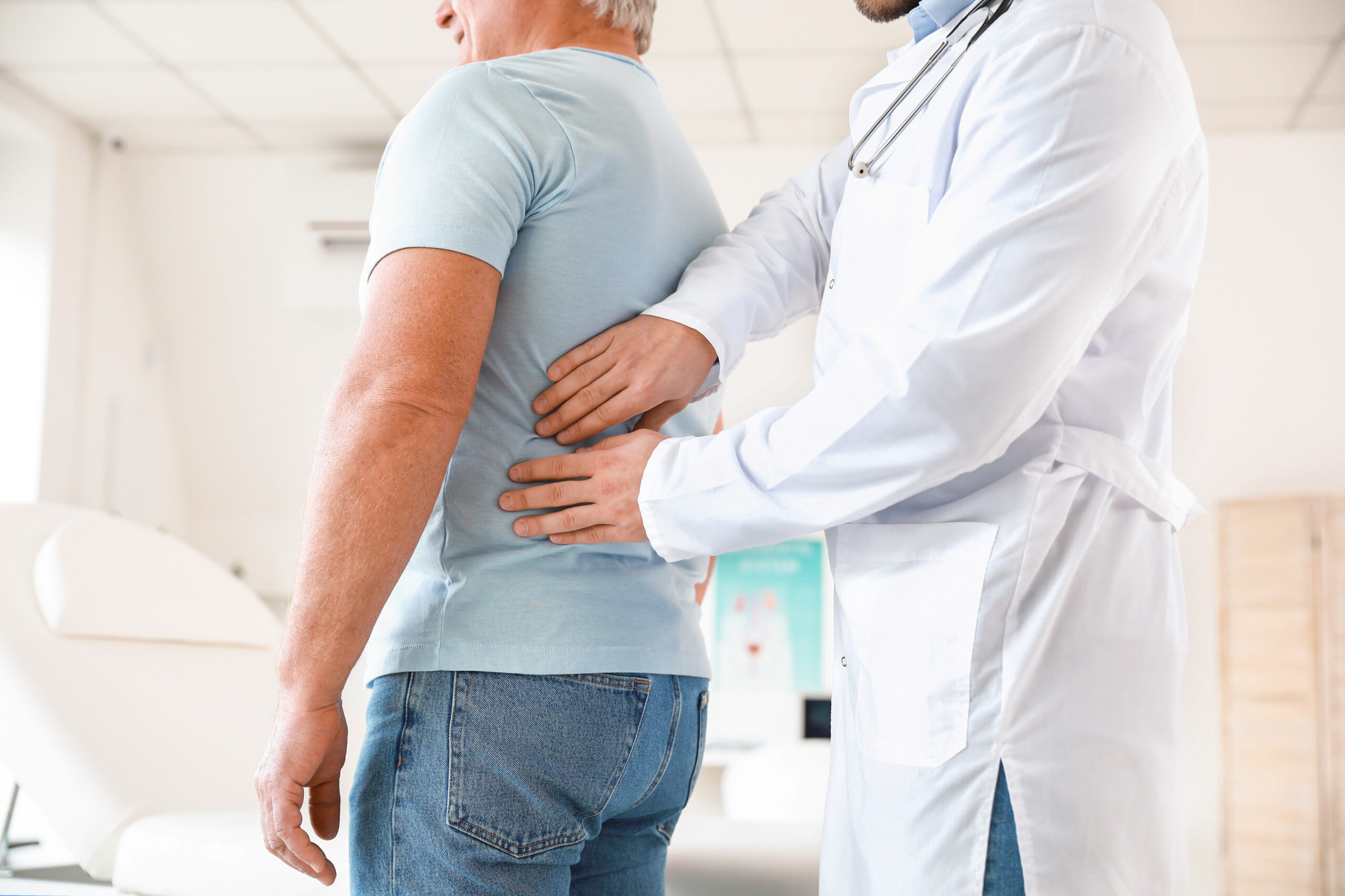 Urologist examining older male patient in clinic