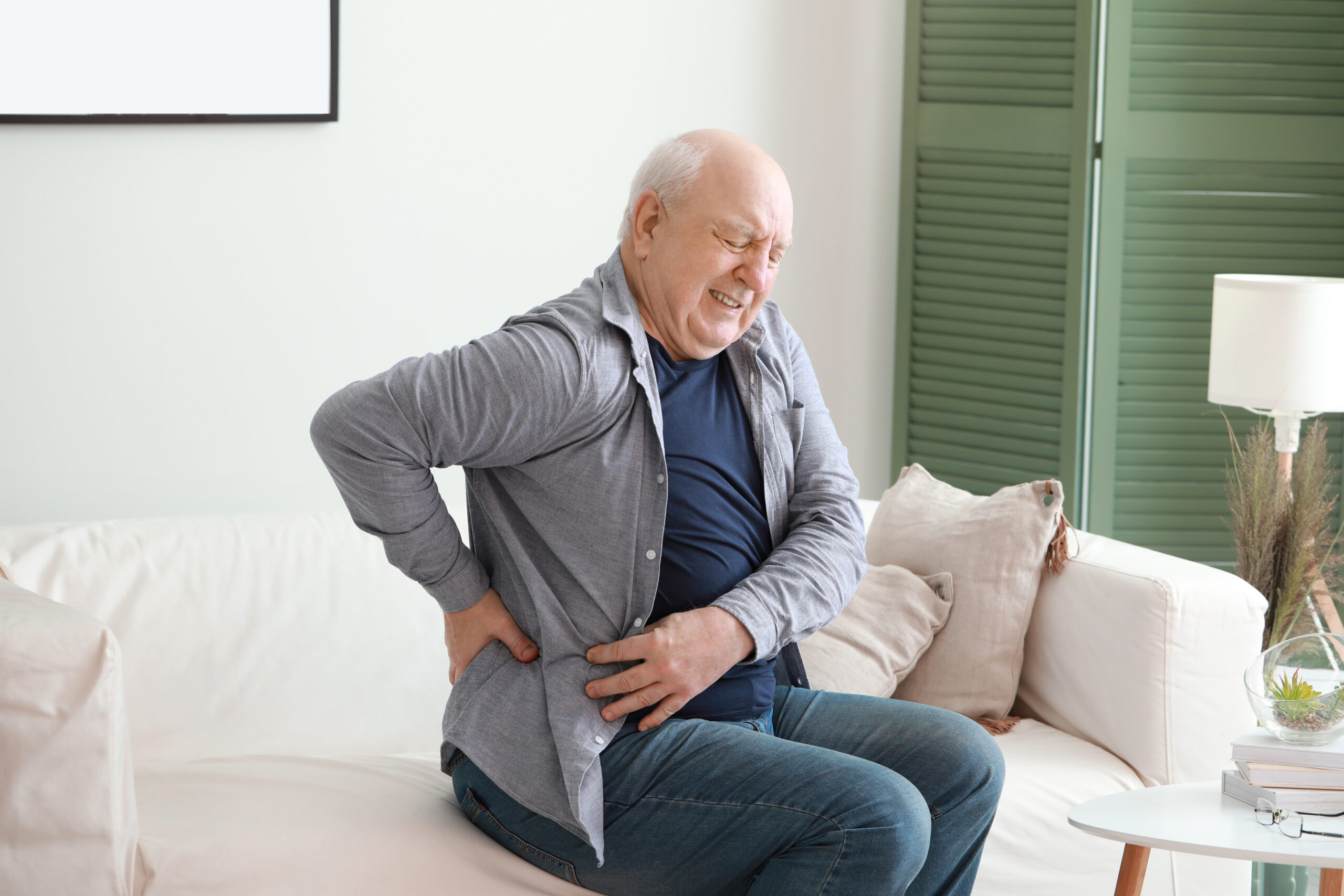 Older man experiencing back and side pain at home