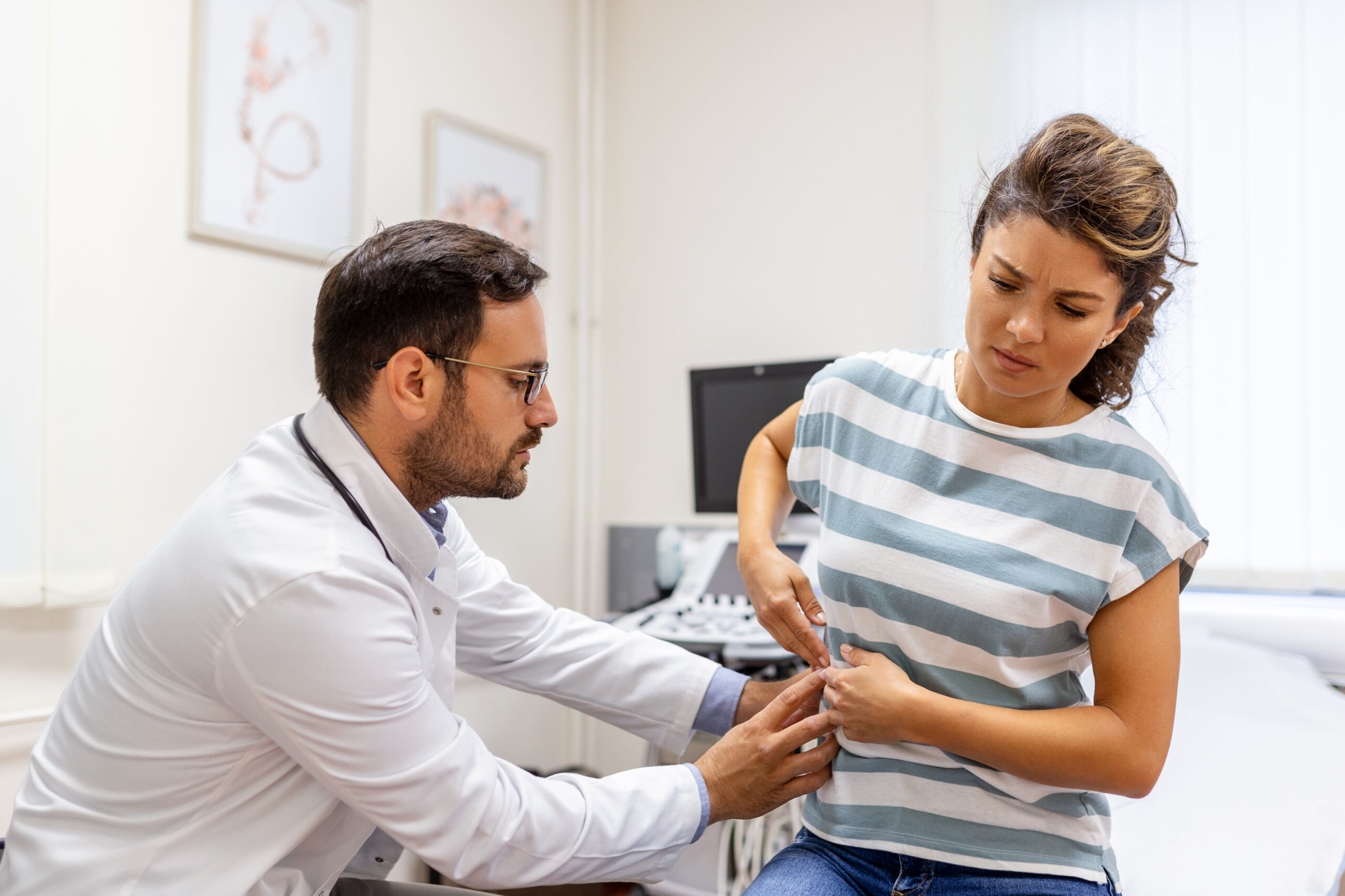 Doctor working with young woman experiencing pain in her side