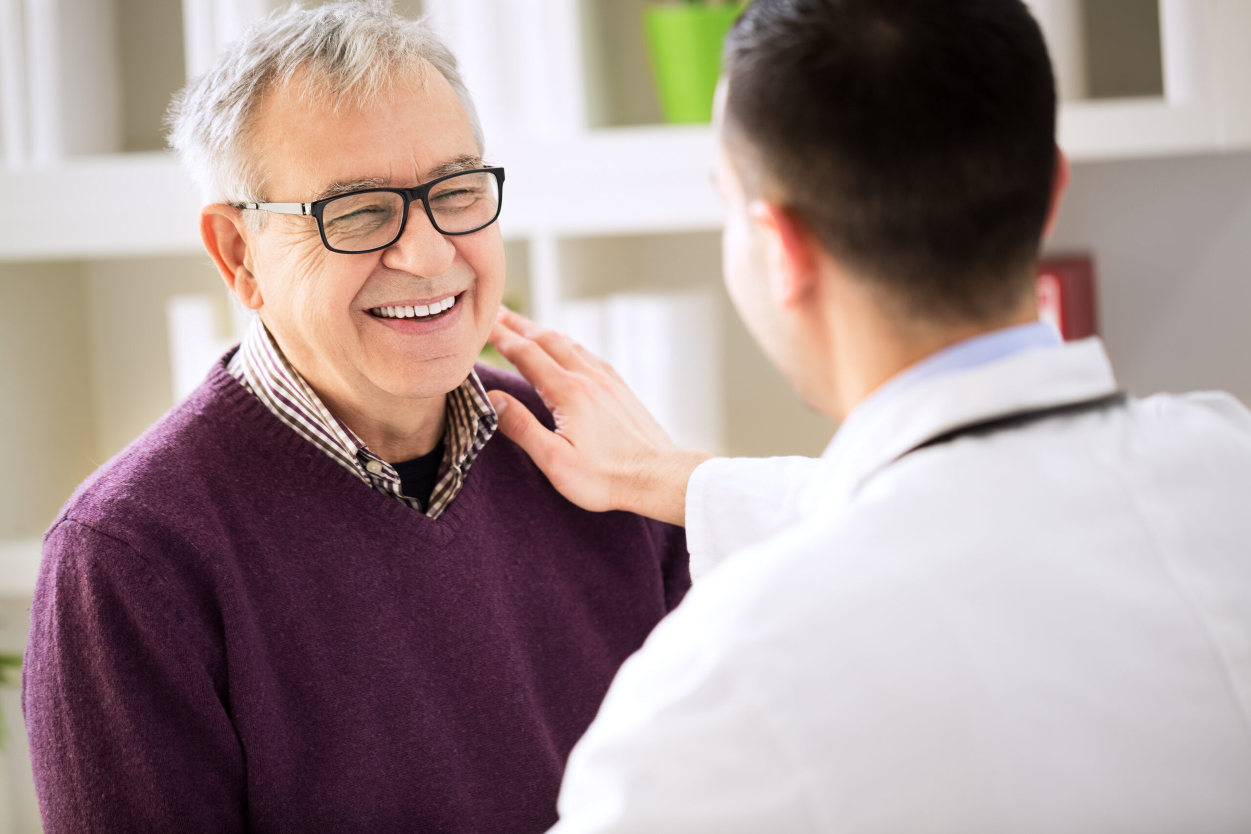 Older man smiling while talking to doctor