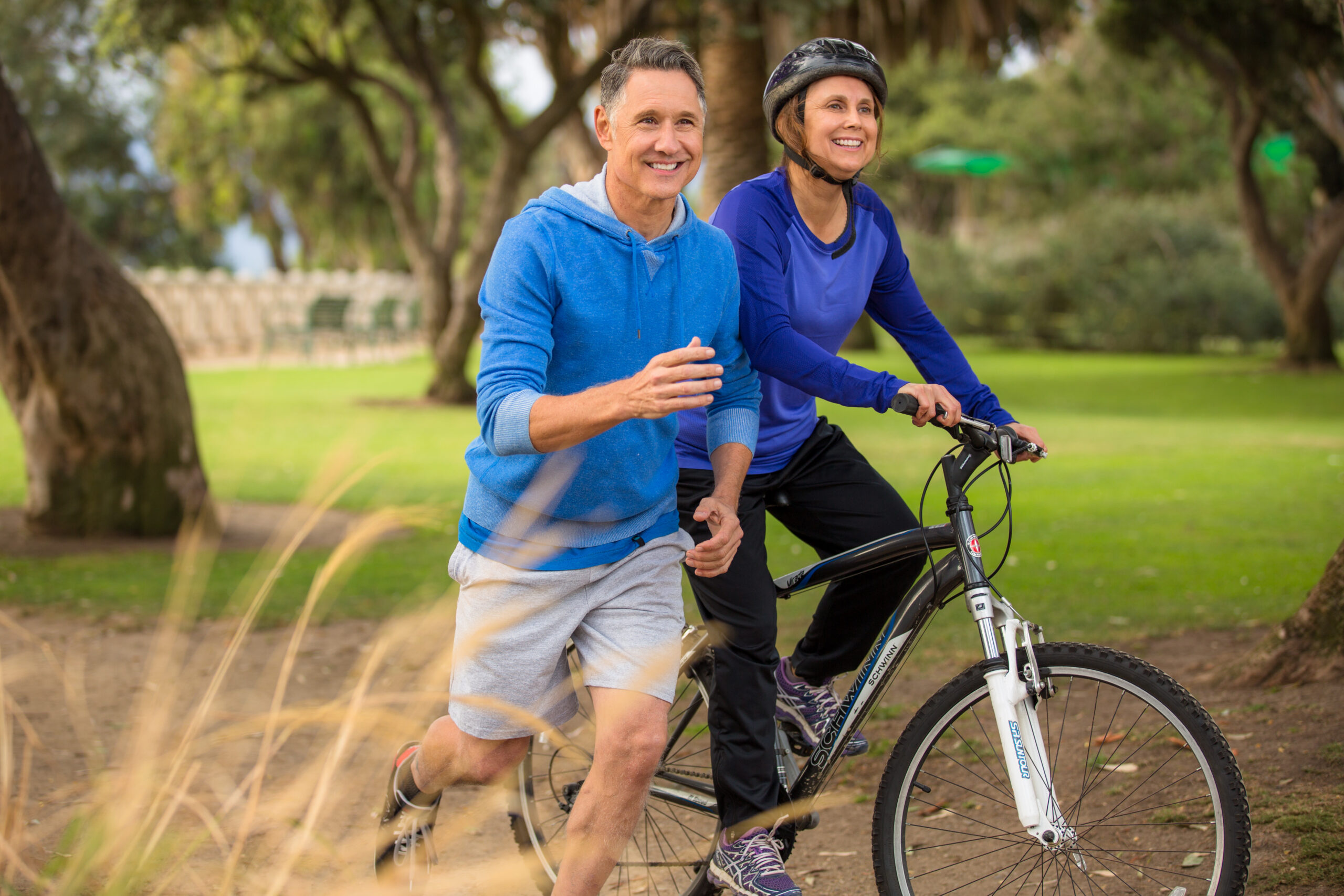 Man jogging alongside woman on bicycle