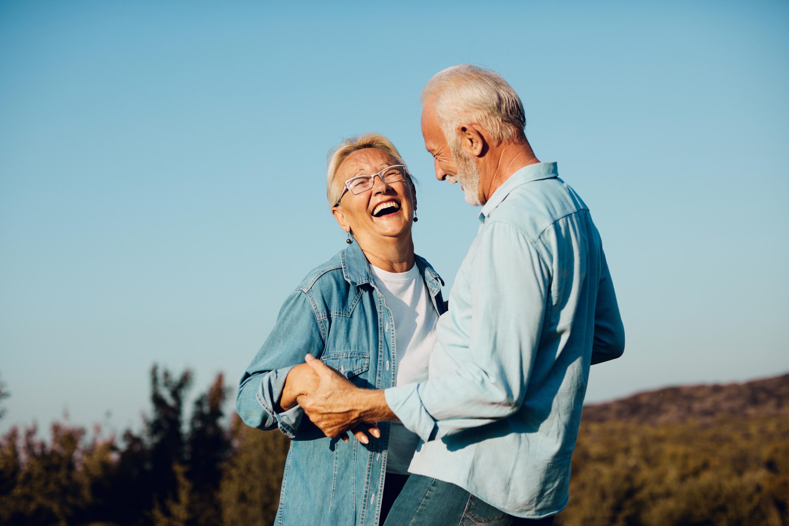 Older couple smiling and holding hands outside